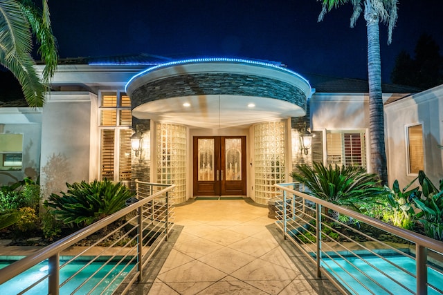 exterior entry at twilight featuring french doors and a balcony