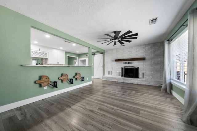 2648 Tremonto Rd, Anderson, CA 96007 - unfurnished living room featuring wood finished floors, a ceiling fan, visible vents, a textured ceiling, and a brick fireplace