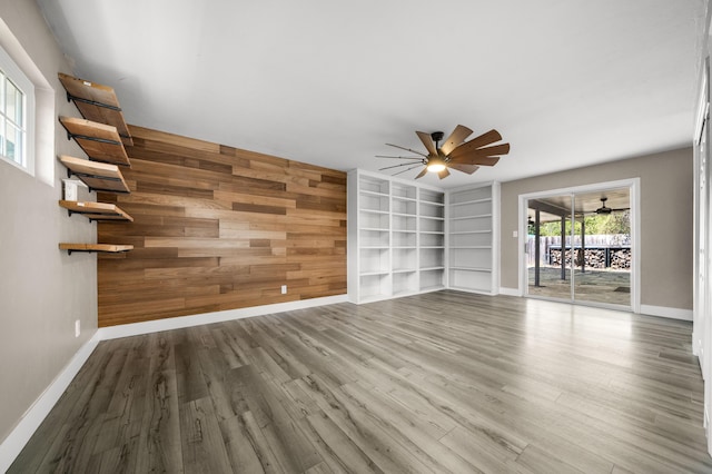 2648 Tremonto Rd, Anderson, CA 96007 - unfurnished living room featuring a ceiling fan, wood finished floors, wooden walls, baseboards, and an accent wall