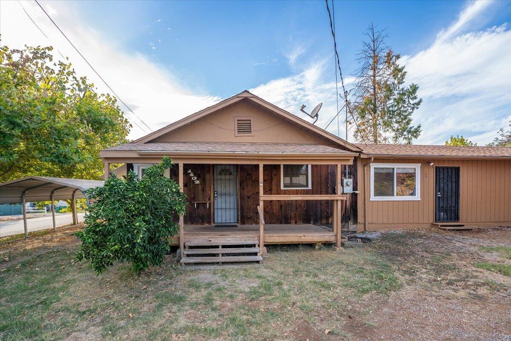 view of front of house featuring a front yard, a wooden deck, and a carport