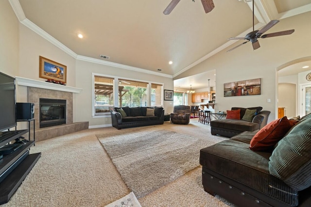 living room with ornamental molding, high vaulted ceiling, a fireplace, light carpet, and ceiling fan with notable chandelier