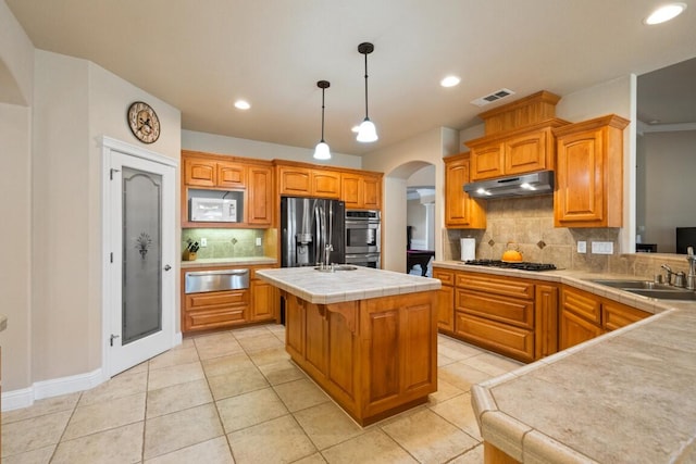 kitchen featuring tasteful backsplash, sink, stainless steel appliances, an island with sink, and light tile patterned floors