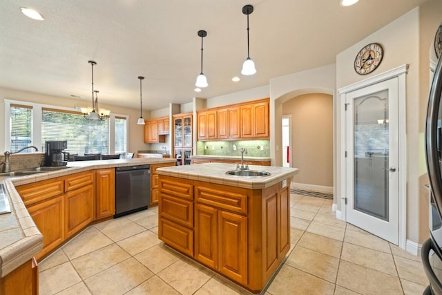 kitchen with hanging light fixtures, black dishwasher, a center island with sink, and sink