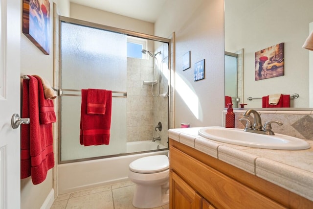 full bathroom featuring shower / bath combination with glass door, vanity, tile patterned flooring, and toilet