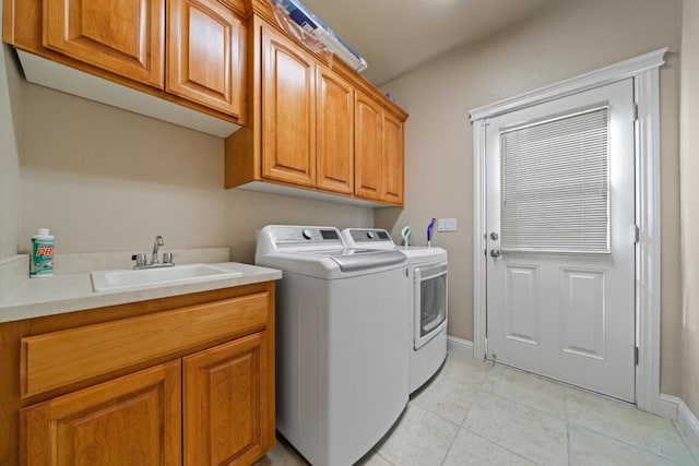 clothes washing area with light tile patterned floors, separate washer and dryer, cabinets, and sink