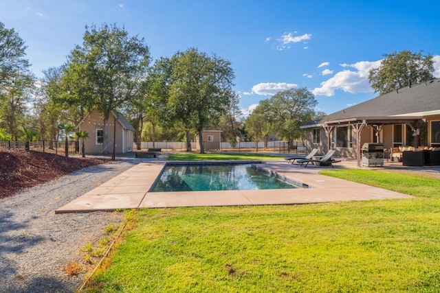 view of swimming pool with a patio, a shed, an outdoor hangout area, a lawn, and grilling area