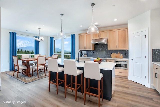 kitchen with light brown cabinets, oven, a healthy amount of sunlight, and light wood-type flooring