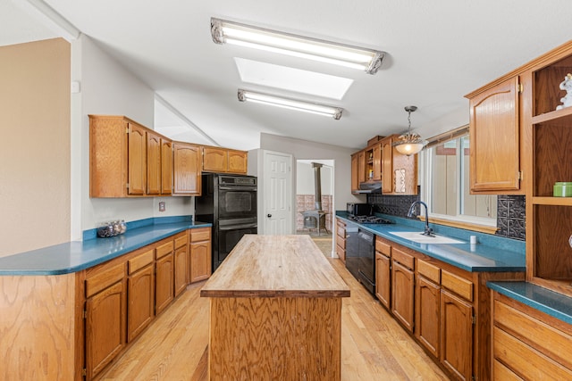 kitchen featuring decorative light fixtures, light hardwood / wood-style flooring, backsplash, black appliances, and a center island