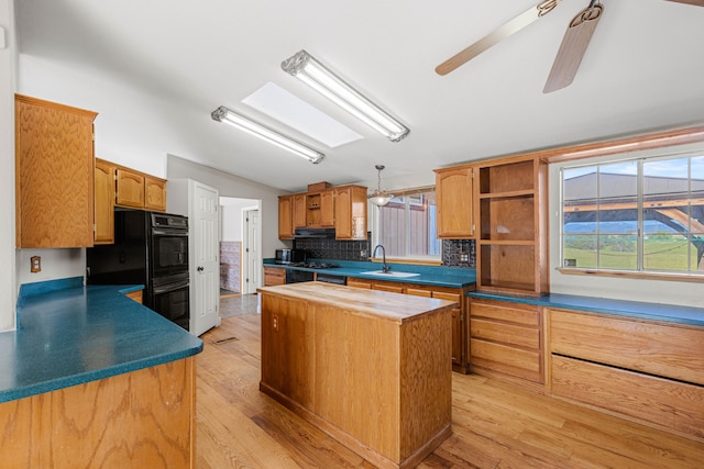 kitchen featuring ceiling fan, tasteful backsplash, a kitchen island, light hardwood / wood-style flooring, and black double oven