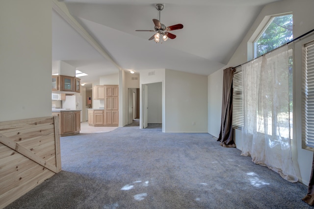 unfurnished living room featuring high vaulted ceiling, ceiling fan, and light colored carpet