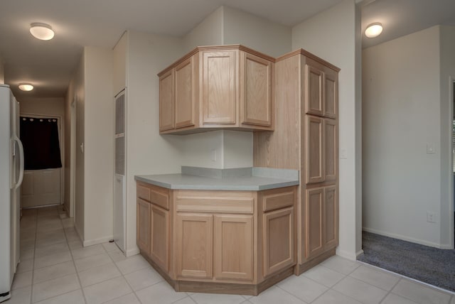 kitchen with light brown cabinetry, white refrigerator with ice dispenser, and light tile patterned floors