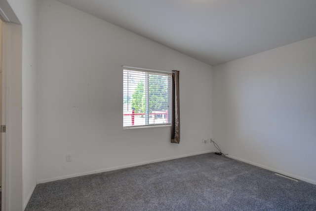 unfurnished room featuring dark carpet and vaulted ceiling