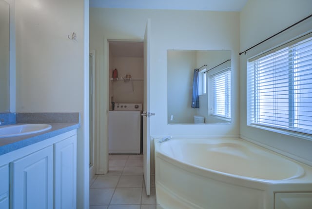 bathroom featuring a bathing tub, tile patterned floors, vanity, and washer / dryer