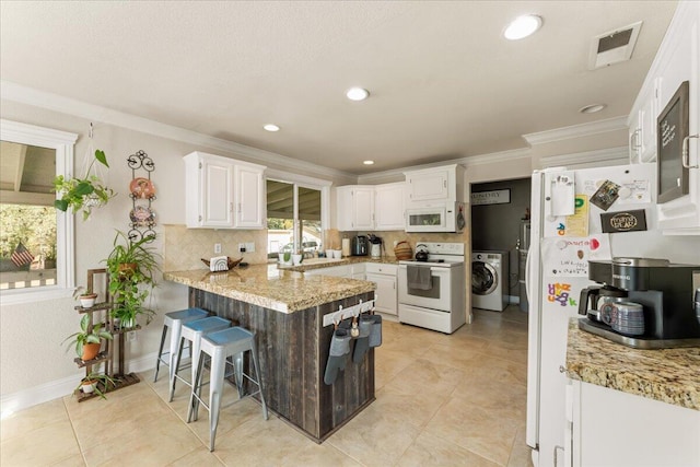 kitchen featuring decorative backsplash, white appliances, white cabinetry, and washer / clothes dryer