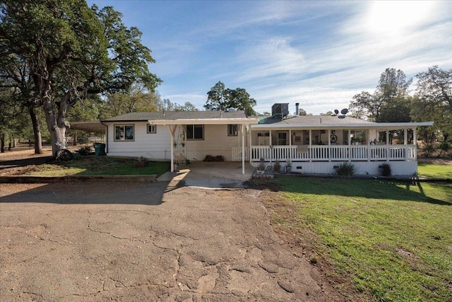 ranch-style home with a front lawn, covered porch, and a carport