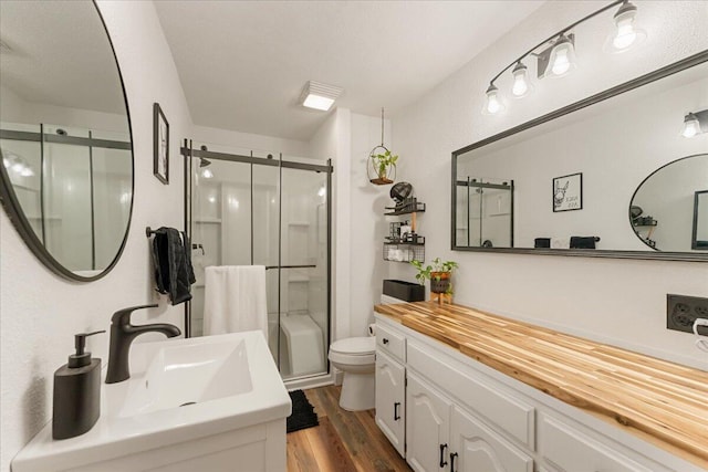 bathroom featuring vanity, hardwood / wood-style floors, toilet, and a shower with door