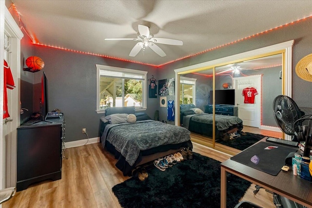 bedroom with a textured ceiling, ceiling fan, a closet, and light hardwood / wood-style flooring