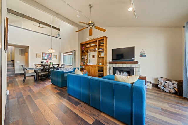 living room featuring a fireplace, dark wood-type flooring, high vaulted ceiling, and rail lighting