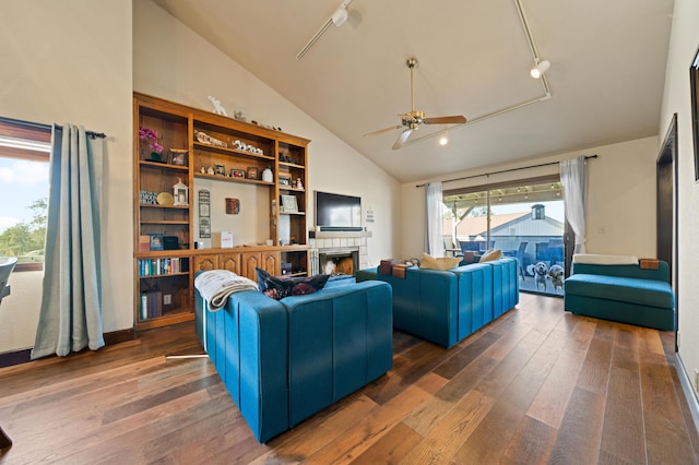 living room with ceiling fan, dark wood-type flooring, high vaulted ceiling, rail lighting, and a fireplace