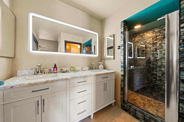 bathroom with vanity, a shower with shower door, and a textured ceiling