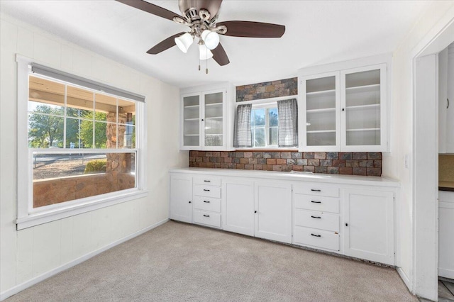 kitchen with light carpet, white cabinets, and plenty of natural light