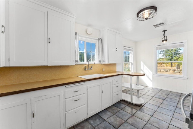 kitchen featuring pendant lighting, tasteful backsplash, white cabinetry, and sink