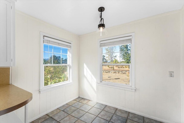 unfurnished dining area featuring plenty of natural light and crown molding