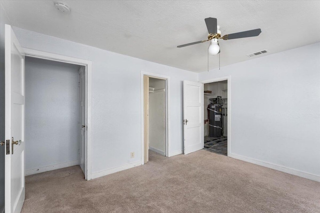 unfurnished bedroom with ceiling fan, a closet, light colored carpet, and a textured ceiling