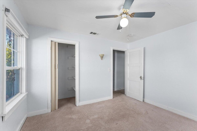 unfurnished bedroom featuring ceiling fan, a closet, light carpet, and a spacious closet