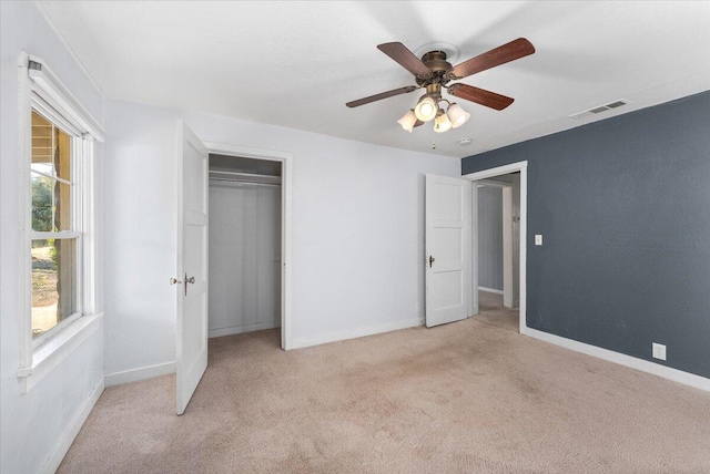 unfurnished bedroom with multiple windows, light carpet, a closet, and ceiling fan