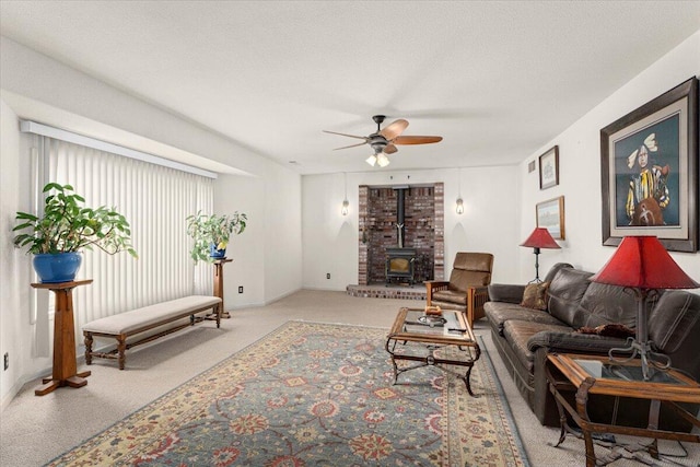 living room with ceiling fan, light colored carpet, a textured ceiling, and a wood stove