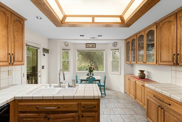 kitchen with tasteful backsplash, sink, tile countertops, kitchen peninsula, and dishwasher