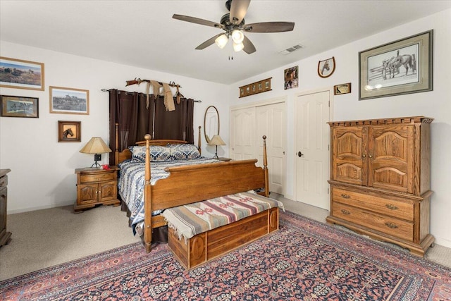 carpeted bedroom with ceiling fan and two closets