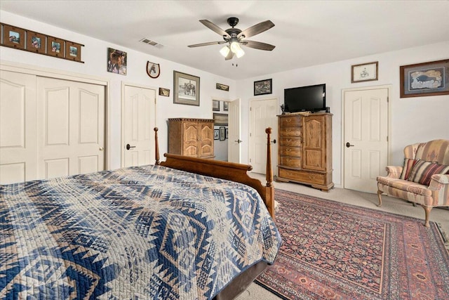 carpeted bedroom featuring ceiling fan and multiple closets