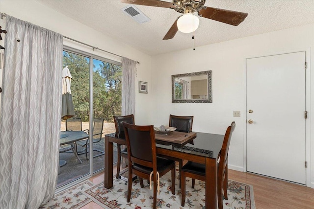 dining area featuring light wood-type flooring, ceiling fan, and a textured ceiling