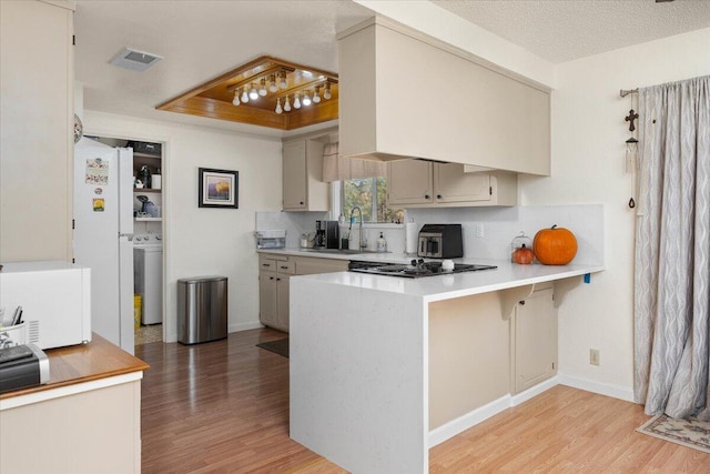 kitchen with a breakfast bar area, light wood-type flooring, sink, and kitchen peninsula