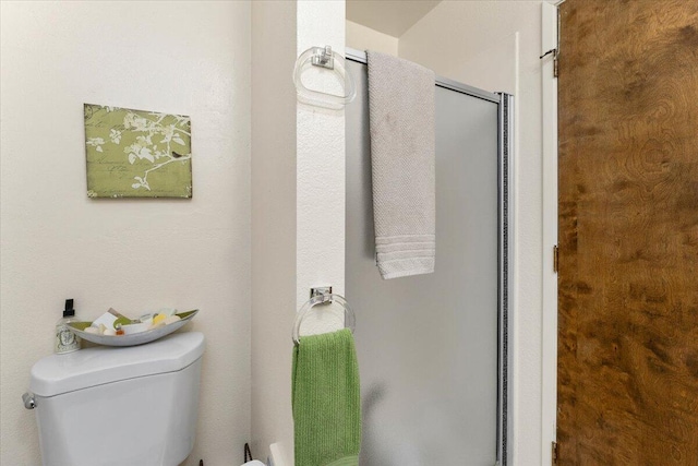 bathroom featuring toilet and a shower with door