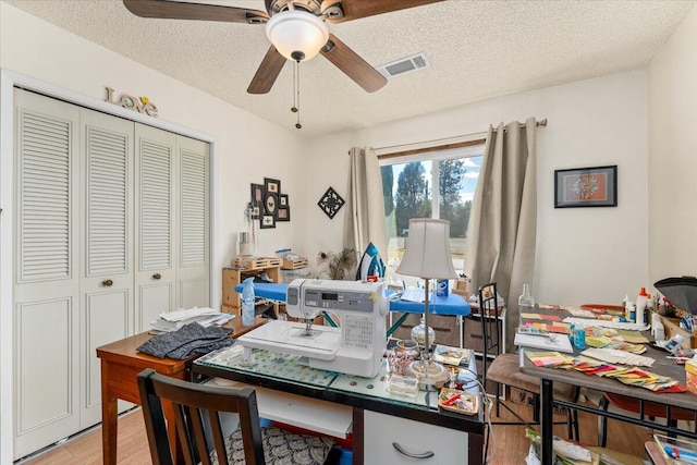 office with ceiling fan, light wood-type flooring, and a textured ceiling