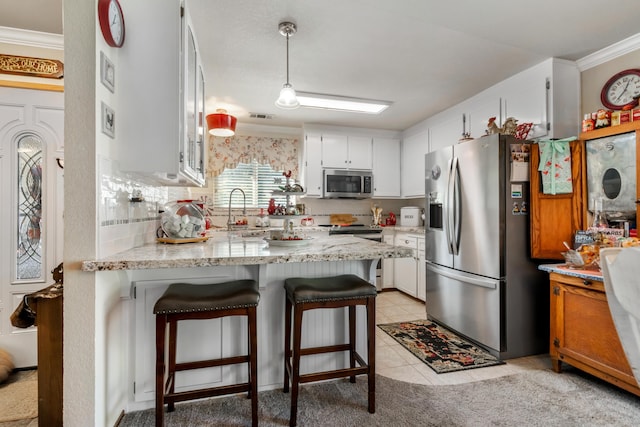 kitchen featuring appliances with stainless steel finishes, hanging light fixtures, white cabinets, sink, and light stone counters