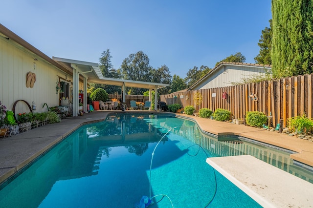 view of pool with a diving board and a patio