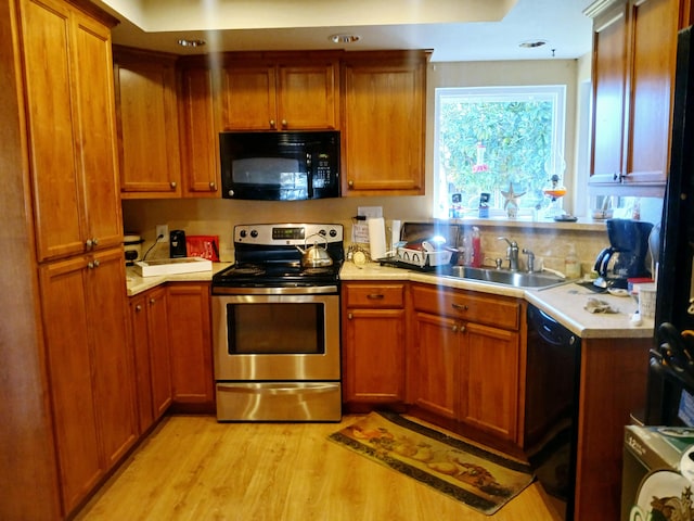 kitchen featuring black appliances, light wood-type flooring, and sink