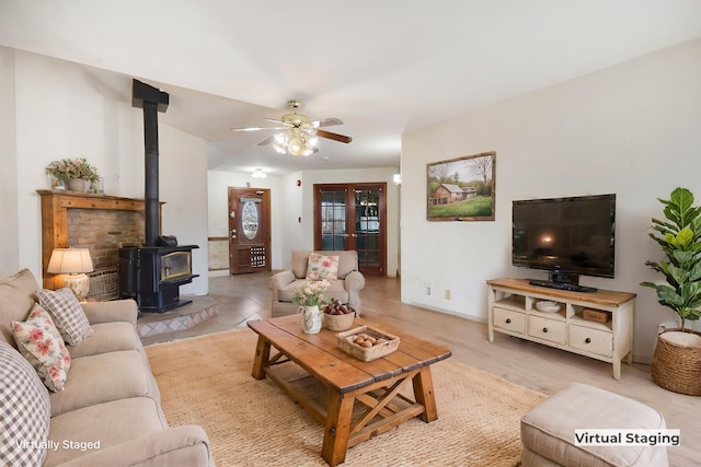 living room featuring a wood stove, ceiling fan, and light hardwood / wood-style flooring