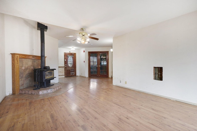 unfurnished living room featuring light hardwood / wood-style floors, a wood stove, and ceiling fan