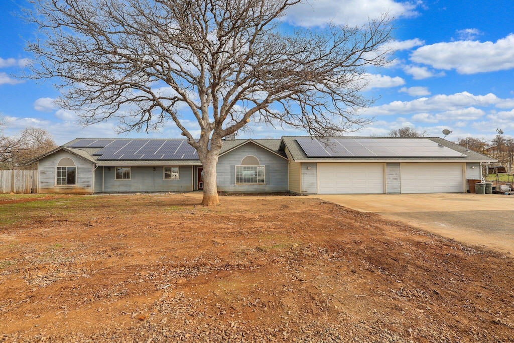 ranch-style house featuring solar panels, cooling unit, and a garage