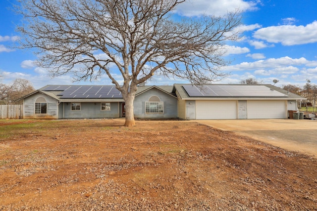 ranch-style house featuring solar panels, cooling unit, and a garage