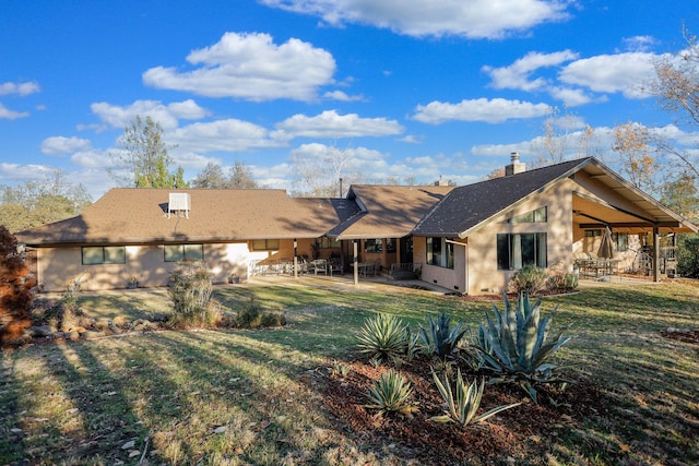 back of property with a yard and a patio