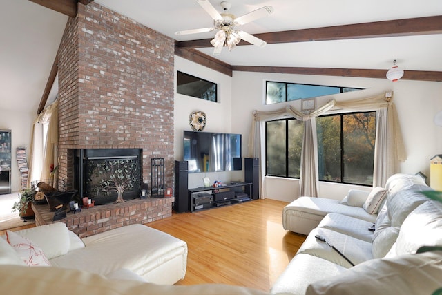 living room with beam ceiling, hardwood / wood-style flooring, ceiling fan, and a brick fireplace