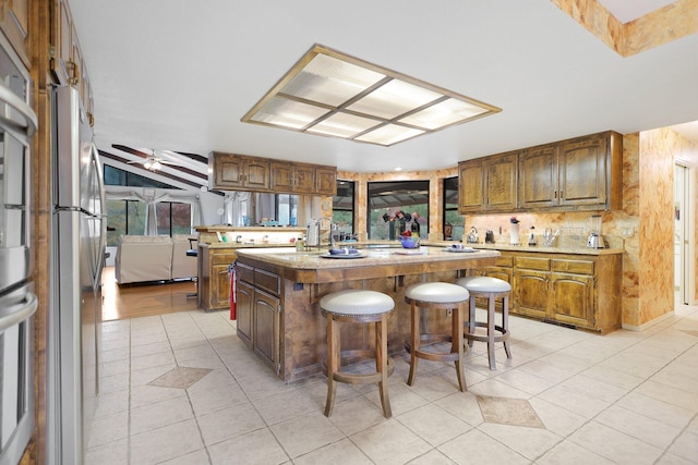 kitchen featuring a breakfast bar, a kitchen island, light tile patterned floors, and ceiling fan