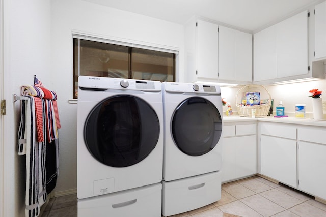 washroom with cabinets, washing machine and dryer, and light tile patterned floors