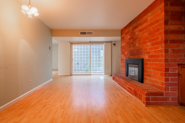 unfurnished living room with hardwood / wood-style floors, a notable chandelier, and a fireplace